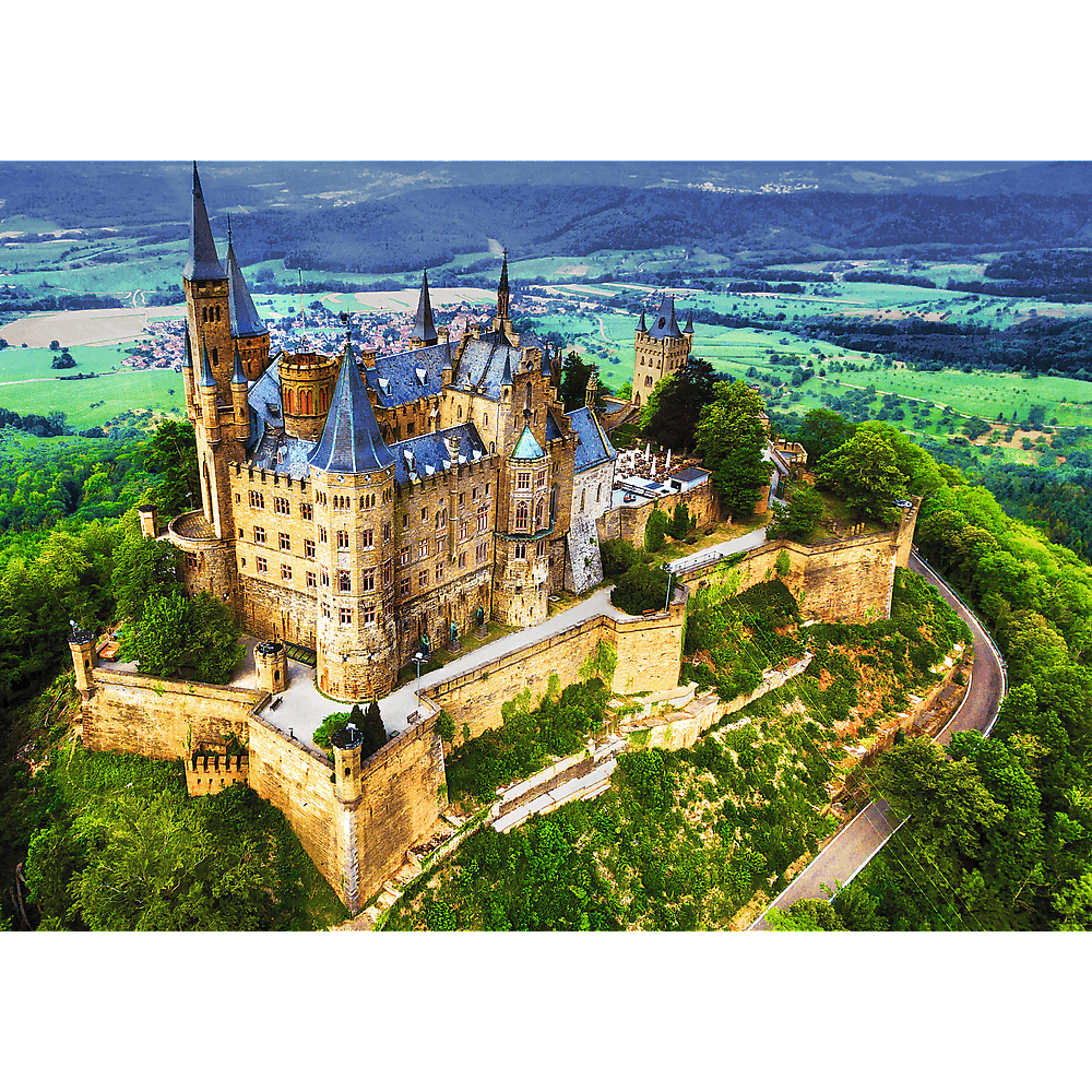 Luftaufnahme eines großen, historischen Schlosses auf einem grünen Hügel mit umliegenden Feldern.
