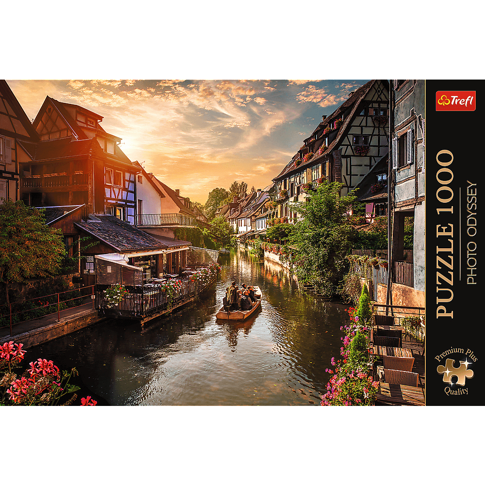 Ein Boot mit Menschen fährt auf einem Kanal zwischen historischen Fachwerkhäusern bei Sonnenuntergang.