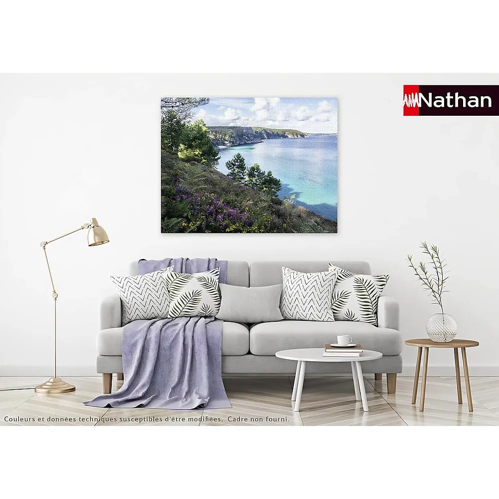 Wohnzimmer mit grauem Sofa, Kissen, Stehlampe, Couchtisch und einem Küsten-Landschaftsbild an der Wand.