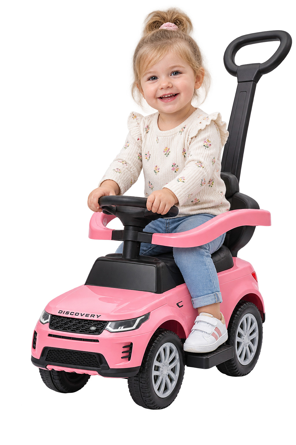 Kleinkind lächelt auf einem rosa Rutschauto mit Griff auf weißem Hintergrund.