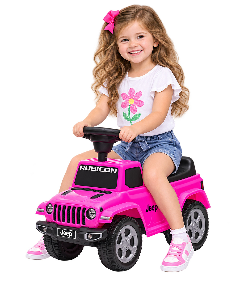 Ein kleines Mädchen mit einer rosa Schleife lächelt und sitzt auf einem rosa Spielzeug-Jeep vor weißem Hintergrund.