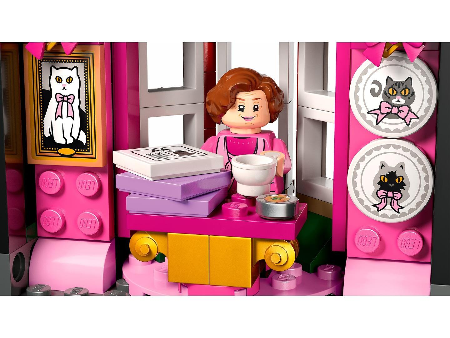 Eine Lego-Minifigur in einem pinken Zimmer mit Katzenbildern, einem Stapel Schachteln und einer Kaffeetasse.