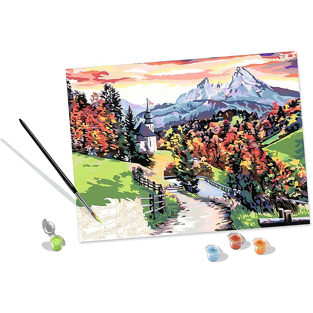 Tela da dipingere con i numeri di un paesaggio alpino con montagne, chiesa, alberi e piccoli vasetti di colore con pennello.