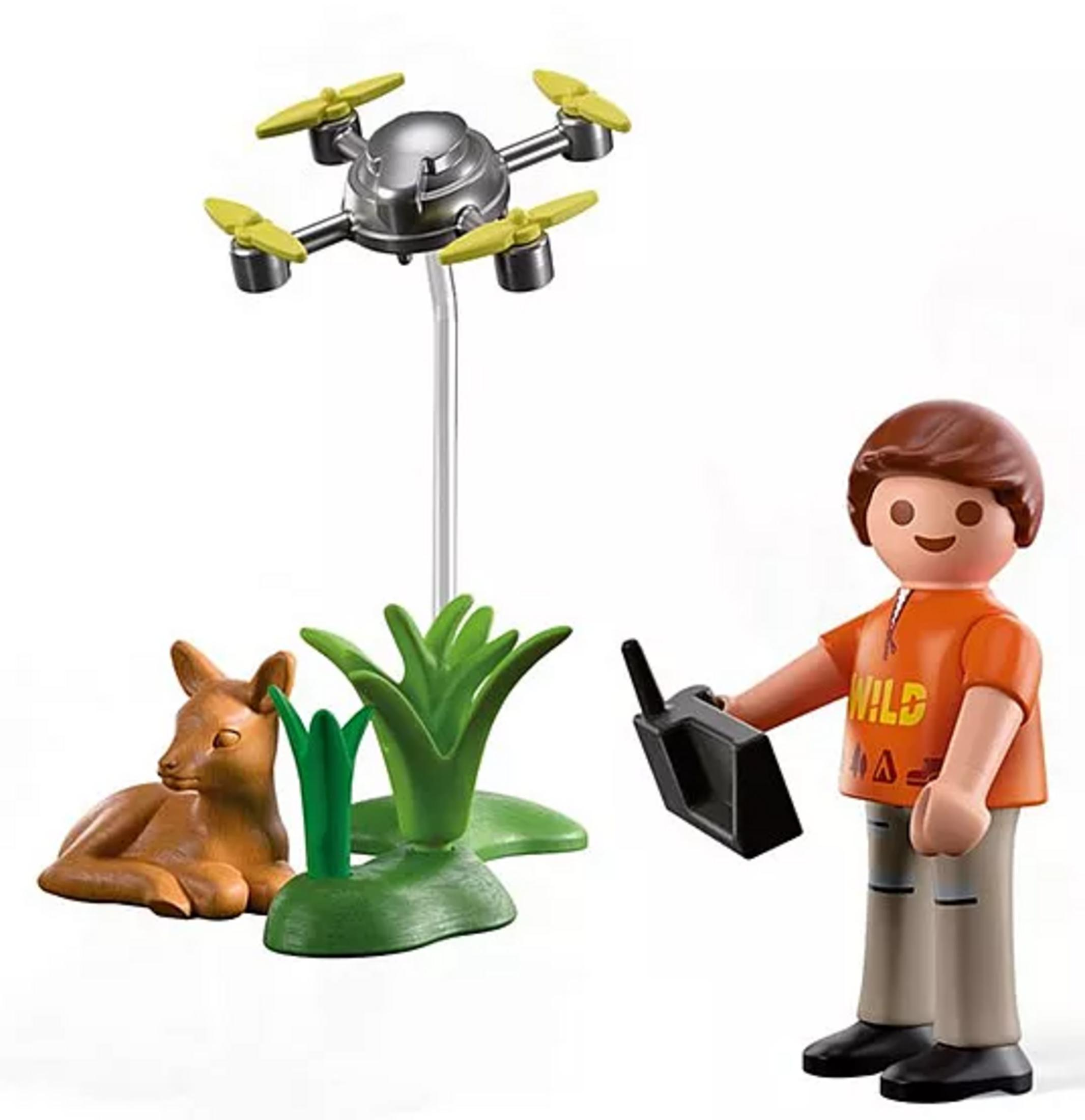 Playmobil-Figur steuert eine Drohne in der Nähe eines liegenden Rehs im Gras.