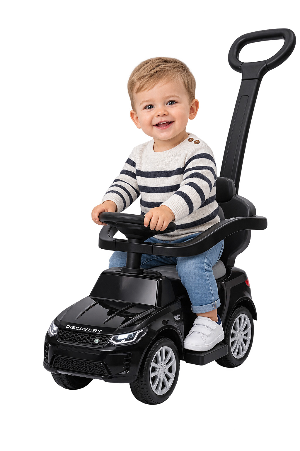 Ein glücklicher Junge sitzt in einem schwarzen Rutschauto mit einer langen Schiebestange.