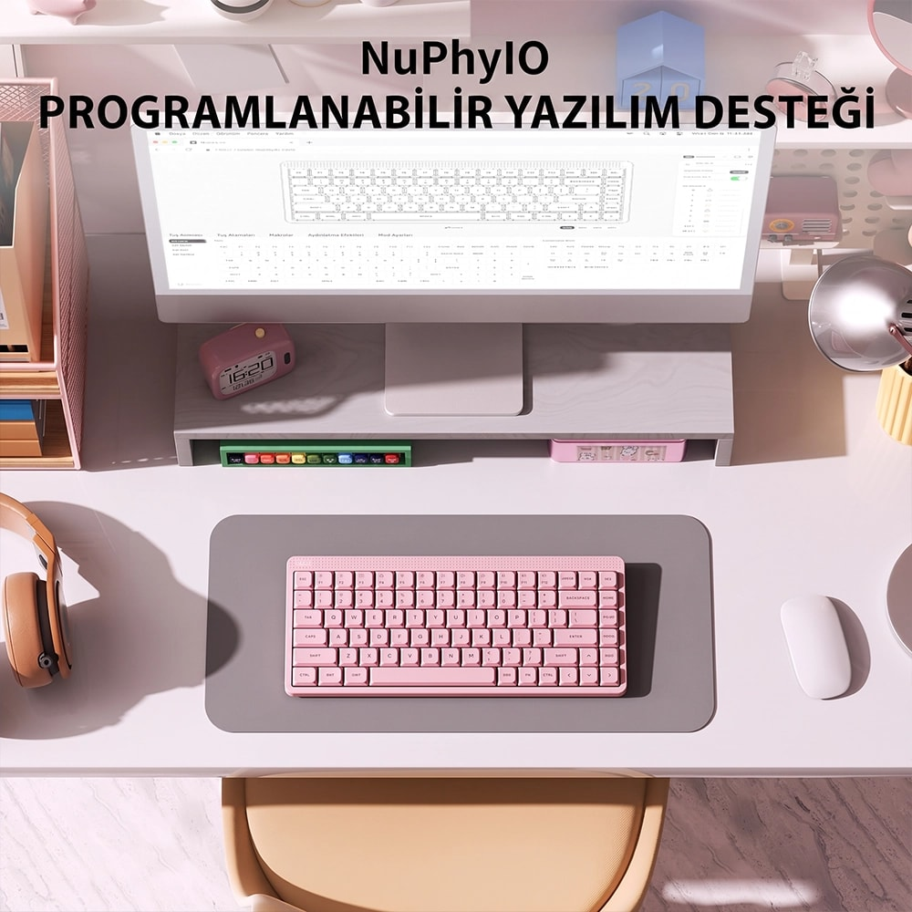 Uporządkowane biurko z różową klawiaturą, monitorem, myszką i słuchawkami.