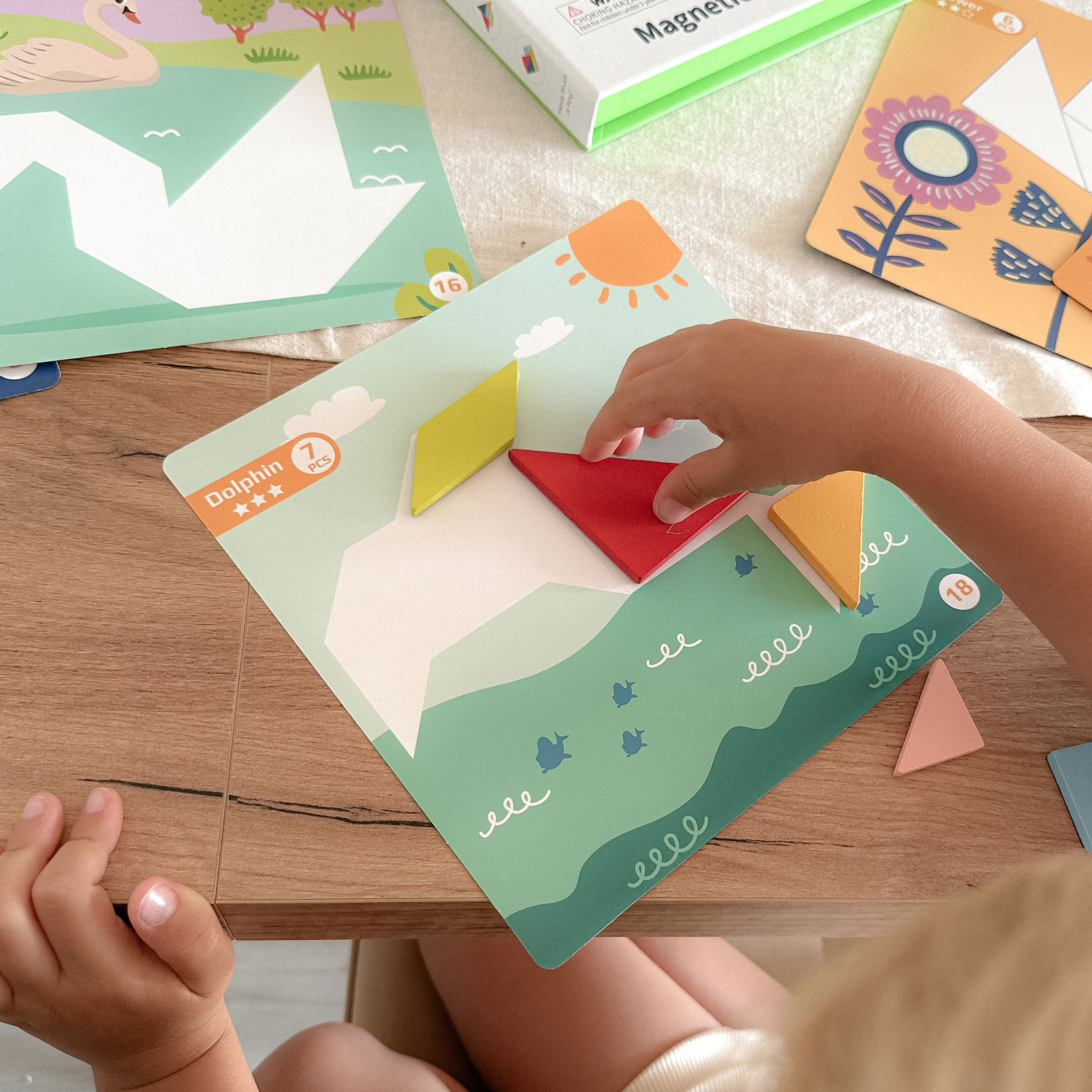 Ein Kind setzt bunte Holzteile in ein Delfin-Puzzle auf einem Holztisch ein.