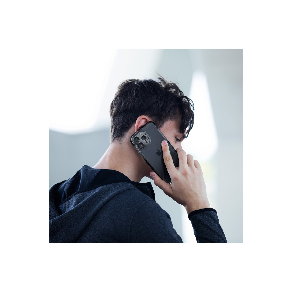 Koyu saçlı genç bir adam akıllı telefonla konuşuyor.