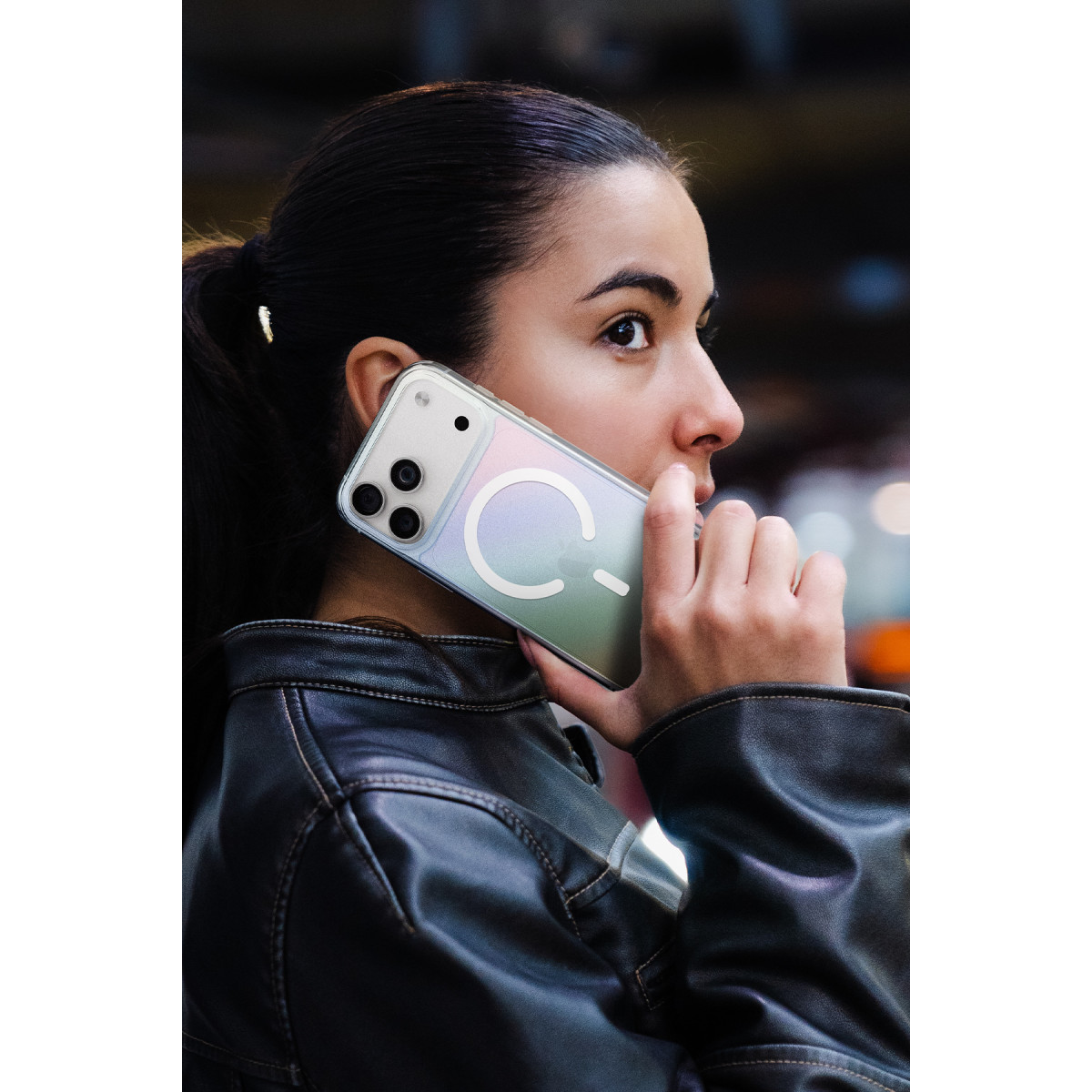 Deri ceketli bir kadın açık renkli bir akıllı telefonla konuşuyor.