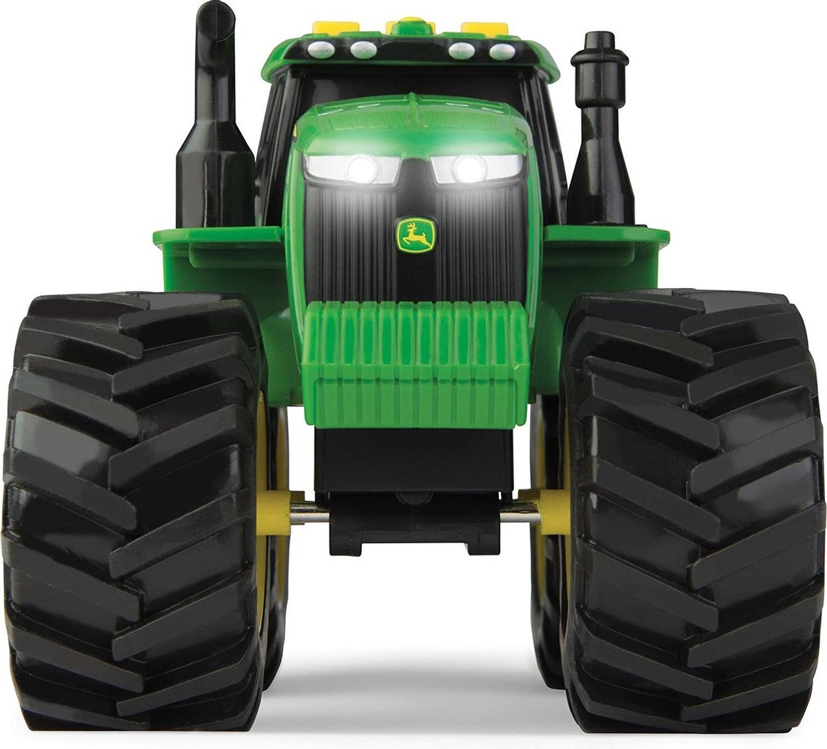 Un tracteur jouet vert et noir avec de gros pneus crantés et des phares avant lumineux.