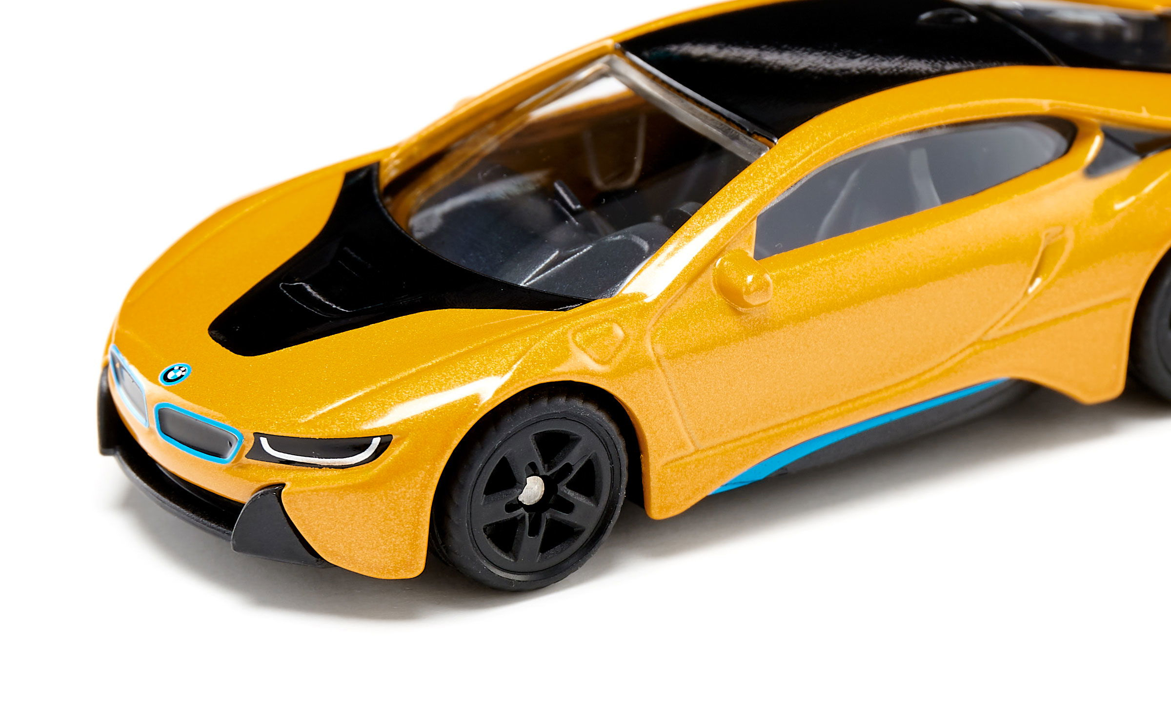 Nahaufnahme eines metallicgelben Spielzeugautos mit schwarzem Dach auf weißem Hintergrund.