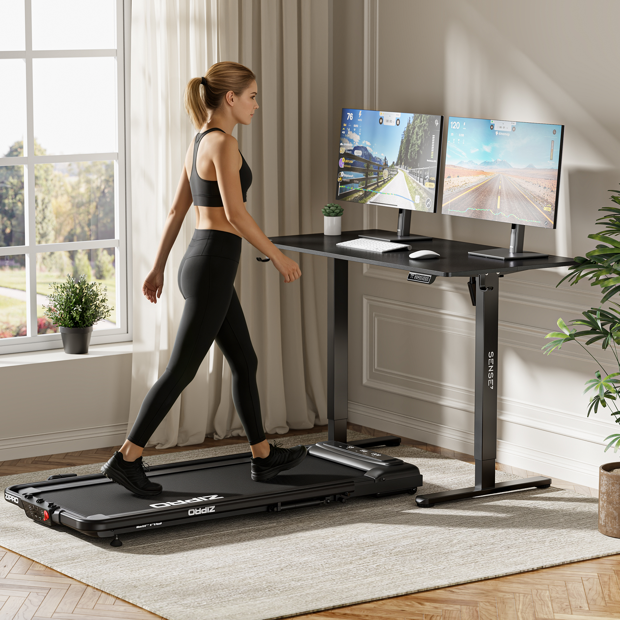 A woman walks on a treadmill before a standing desk with dual monitors displaying virtual outdoor scenes in a bright room.