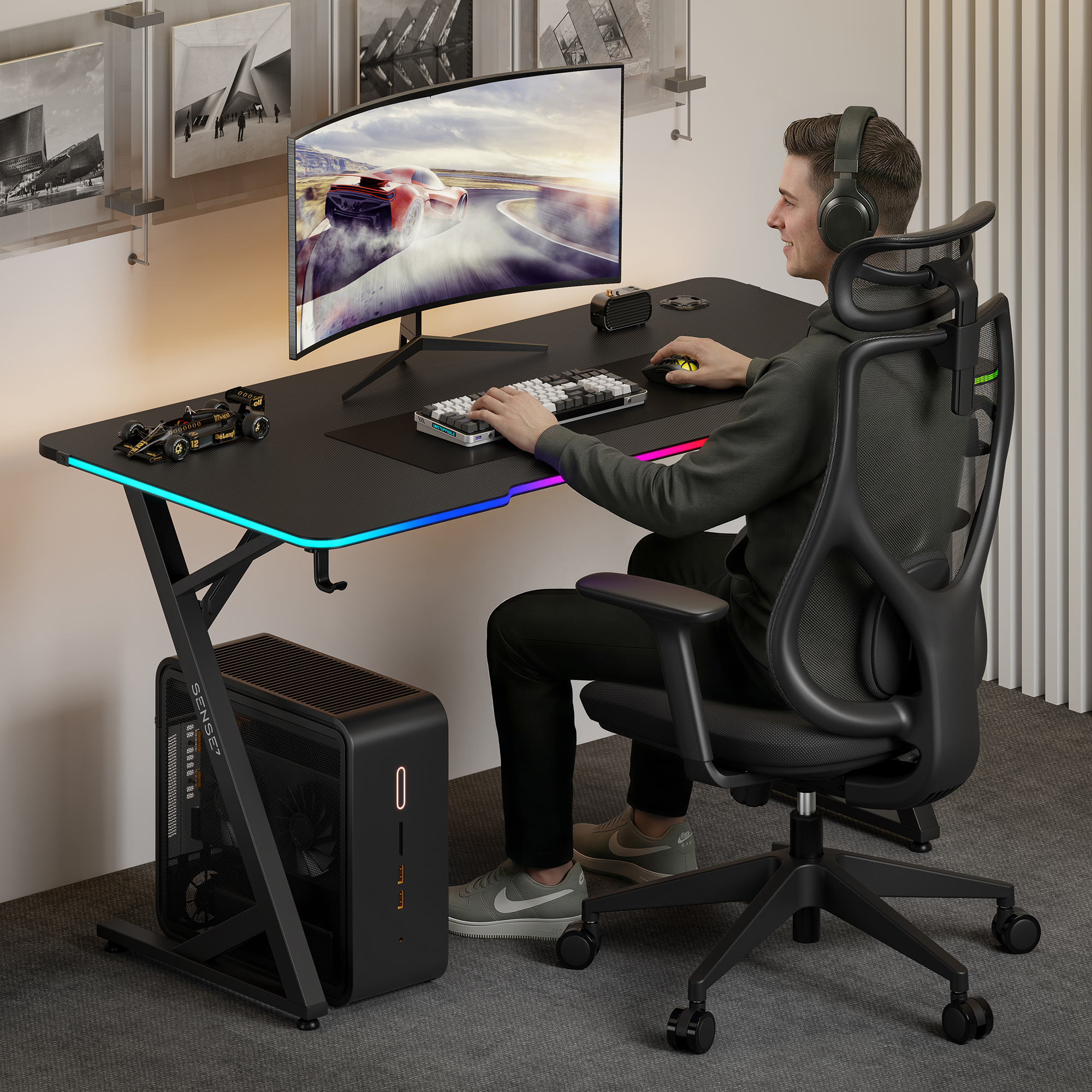 Ein junger Mann sitzt an einem schwarzen Gaming-Schreibtisch, spielt ein Rennspiel auf einem Curved Monitor.