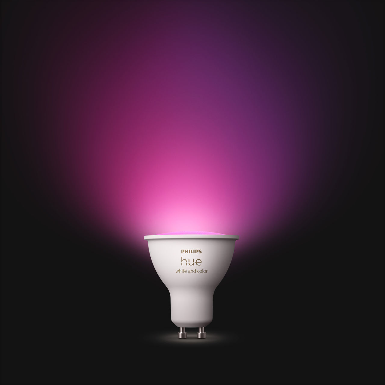 Una lampadina Philips Hue emette una vivace luce rosa e viola su uno sfondo scuro.