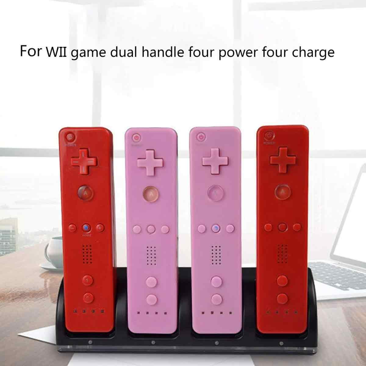 Vier Wii-Controller in rot und rosa stehen in einer schwarzen Ladestation auf einem Holztisch vor einem Fenster.