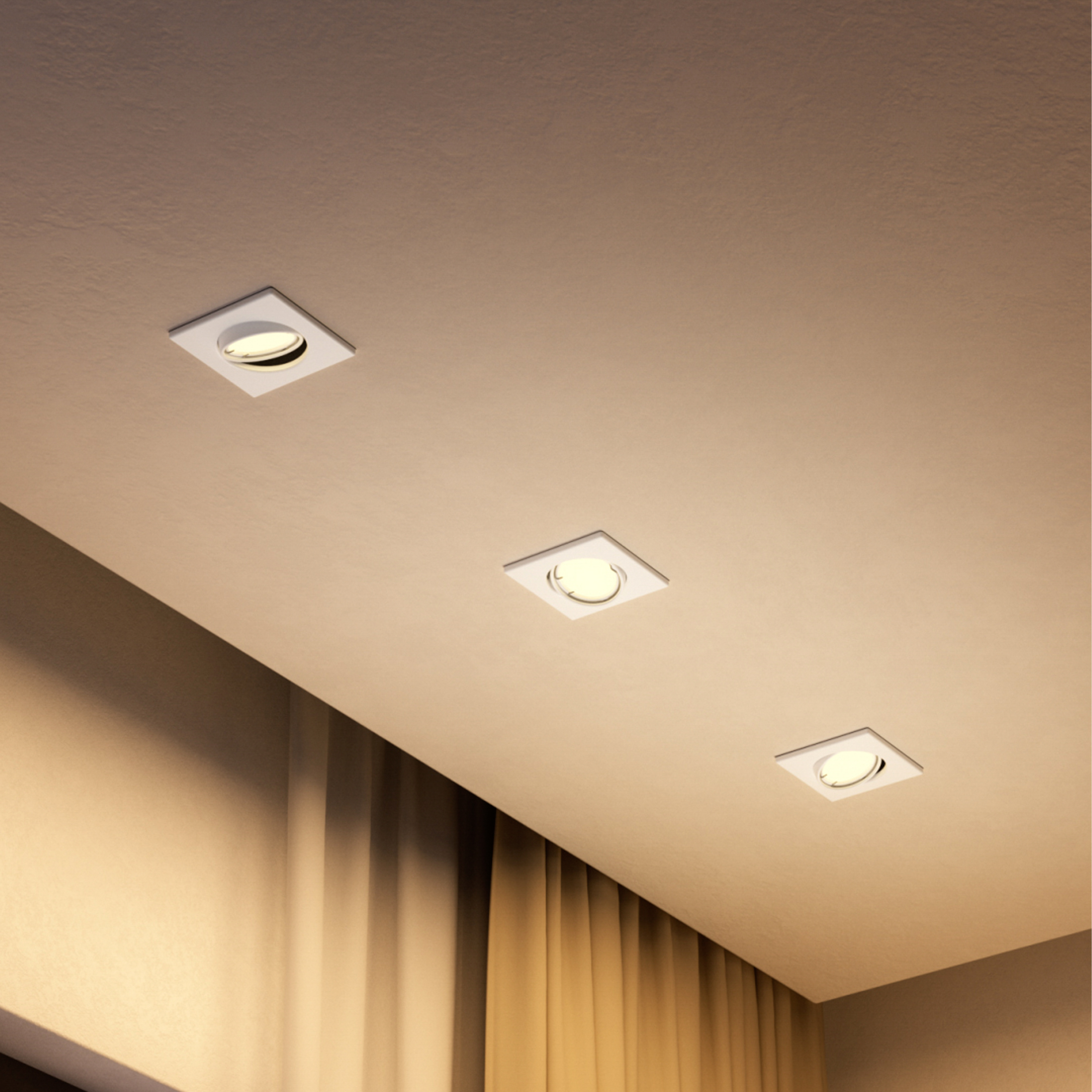 Tre faretti da incasso quadrati brillano caldamente su un soffitto crema sopra le tende.