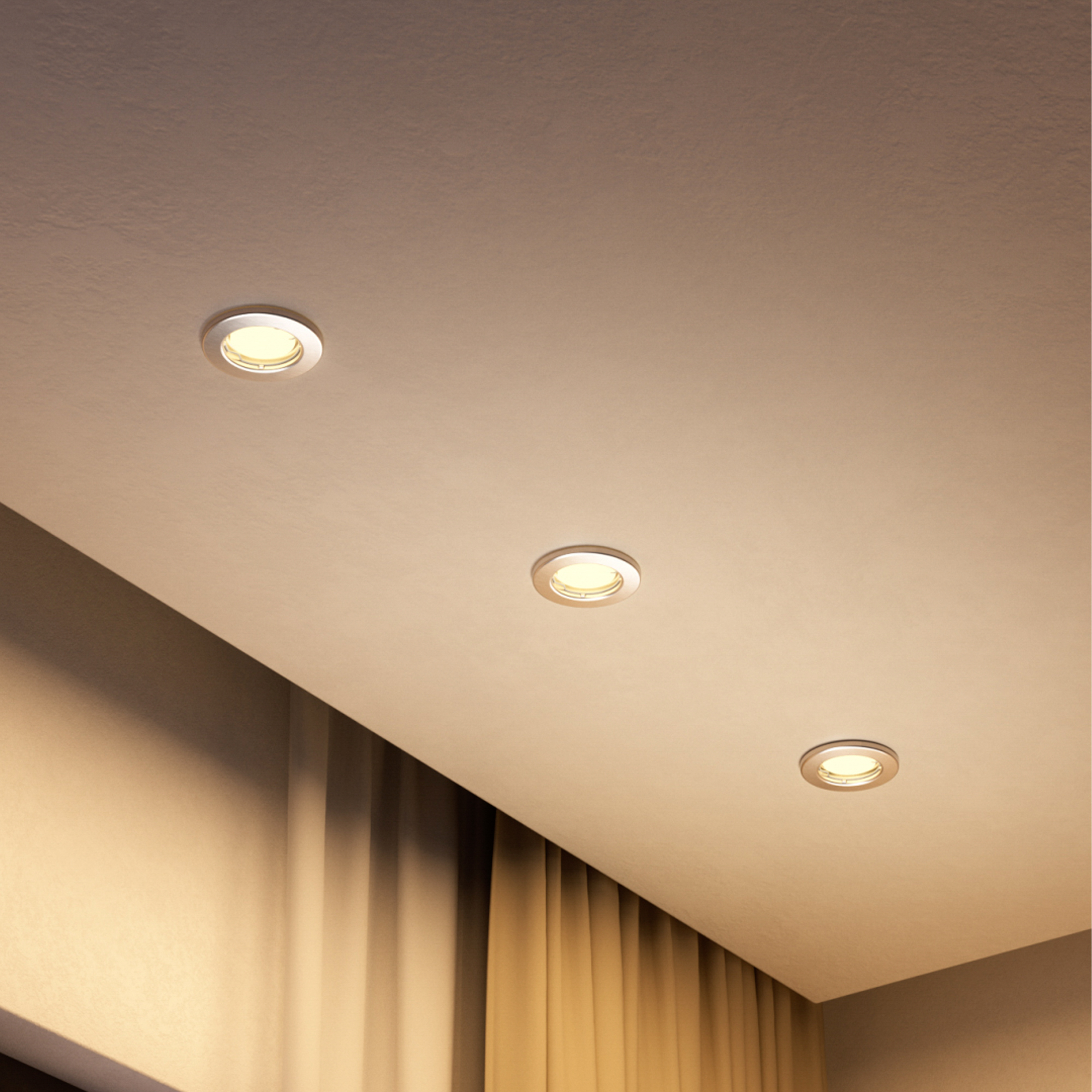Tre faretti da incasso rotondi a luce calda in un soffitto chiaro sopra tende dorate.