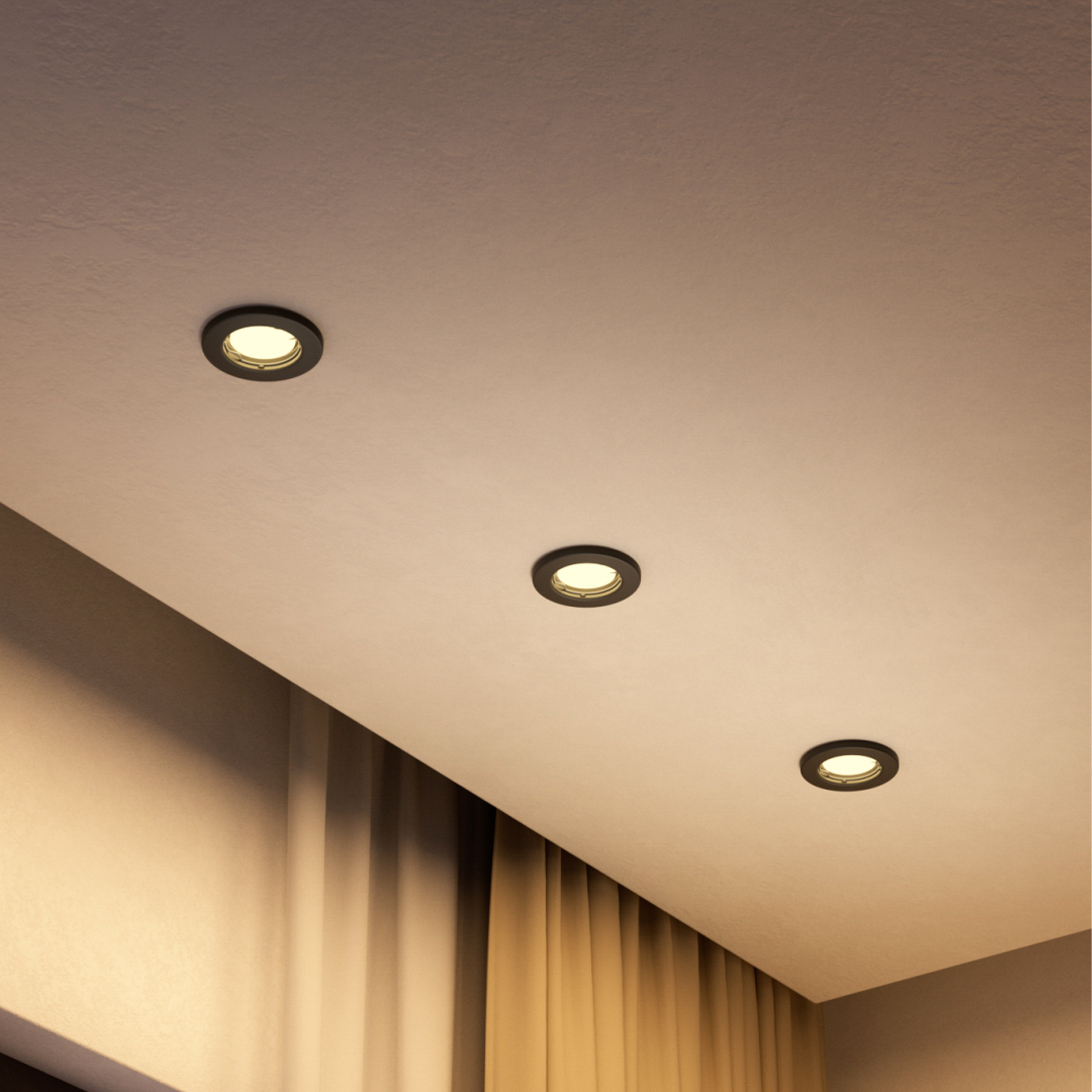 Tre faretti da incasso rotondi e neri illuminano un soffitto bianco sopra le tende.