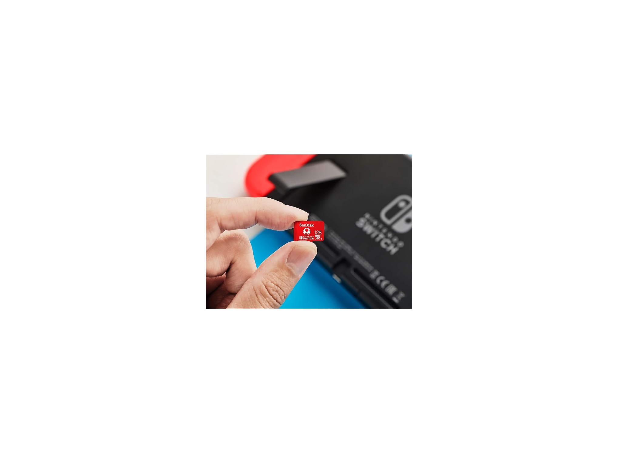 Eine Hand hält eine rote SanDisk 128GB MicroSD-Karte vor eine Nintendo Switch-Konsole.