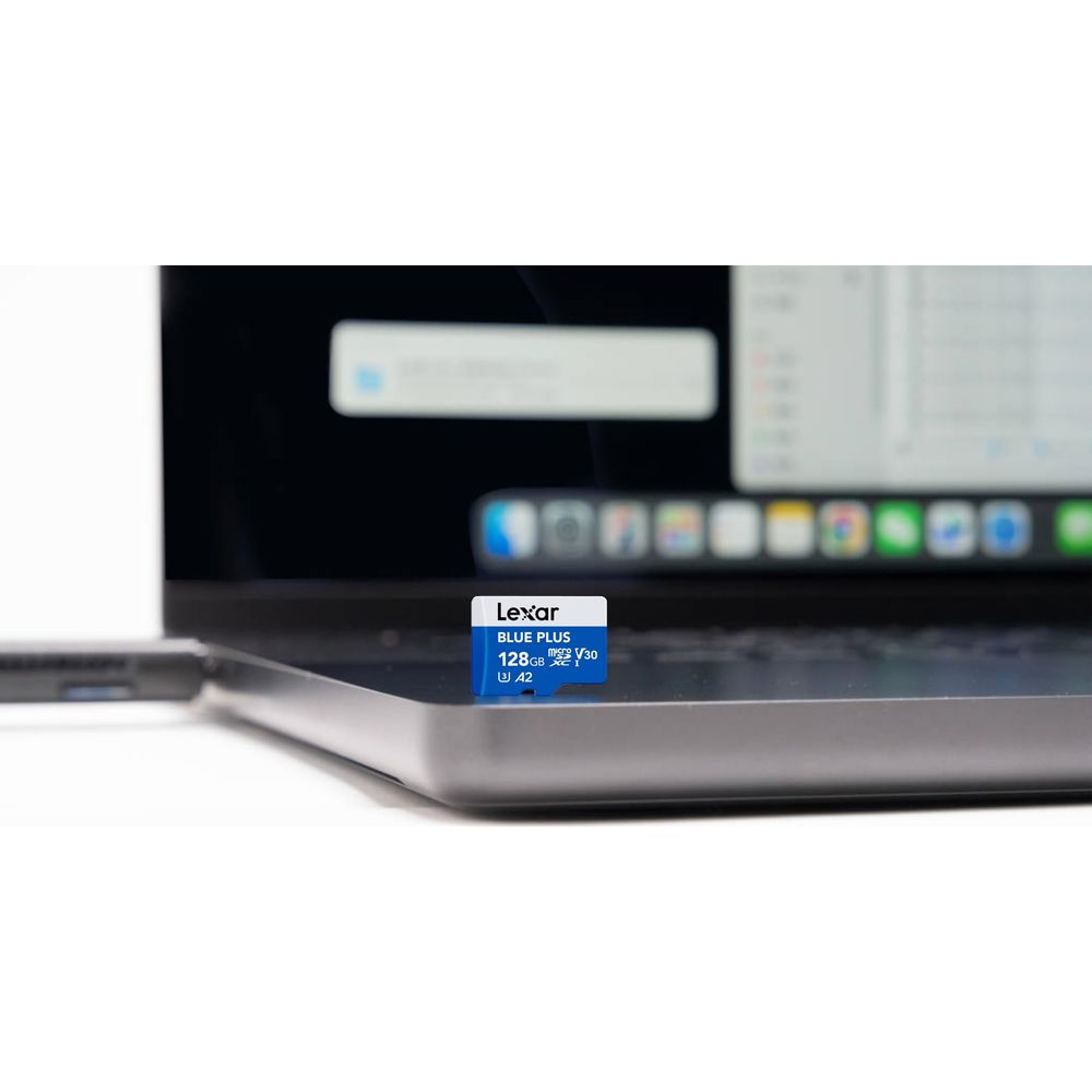 Eine blaue Lexar Blue Plus 128GB MicroSD-Karte liegt auf einem silbernen Laptop in der Nähe eines USB-C-Kabels.