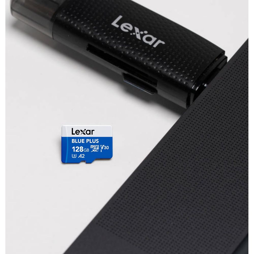 Eine blaue Lexar 128GB microSD-Karte liegt neben einem schwarzen Kartenleser auf weißem Hintergrund.
