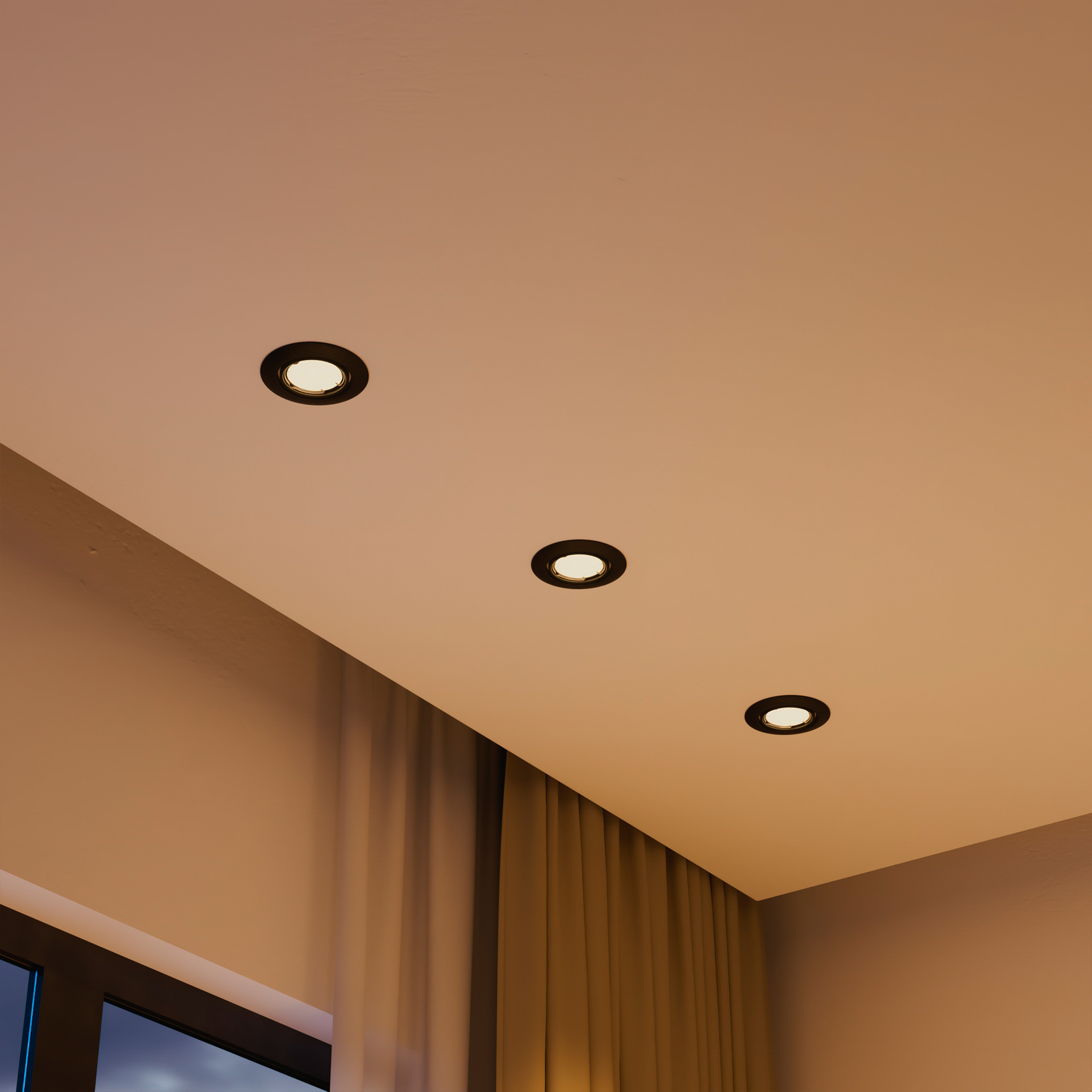 Tre faretti da incasso a soffitto rotondi illuminano una stanza luminosa con tende.