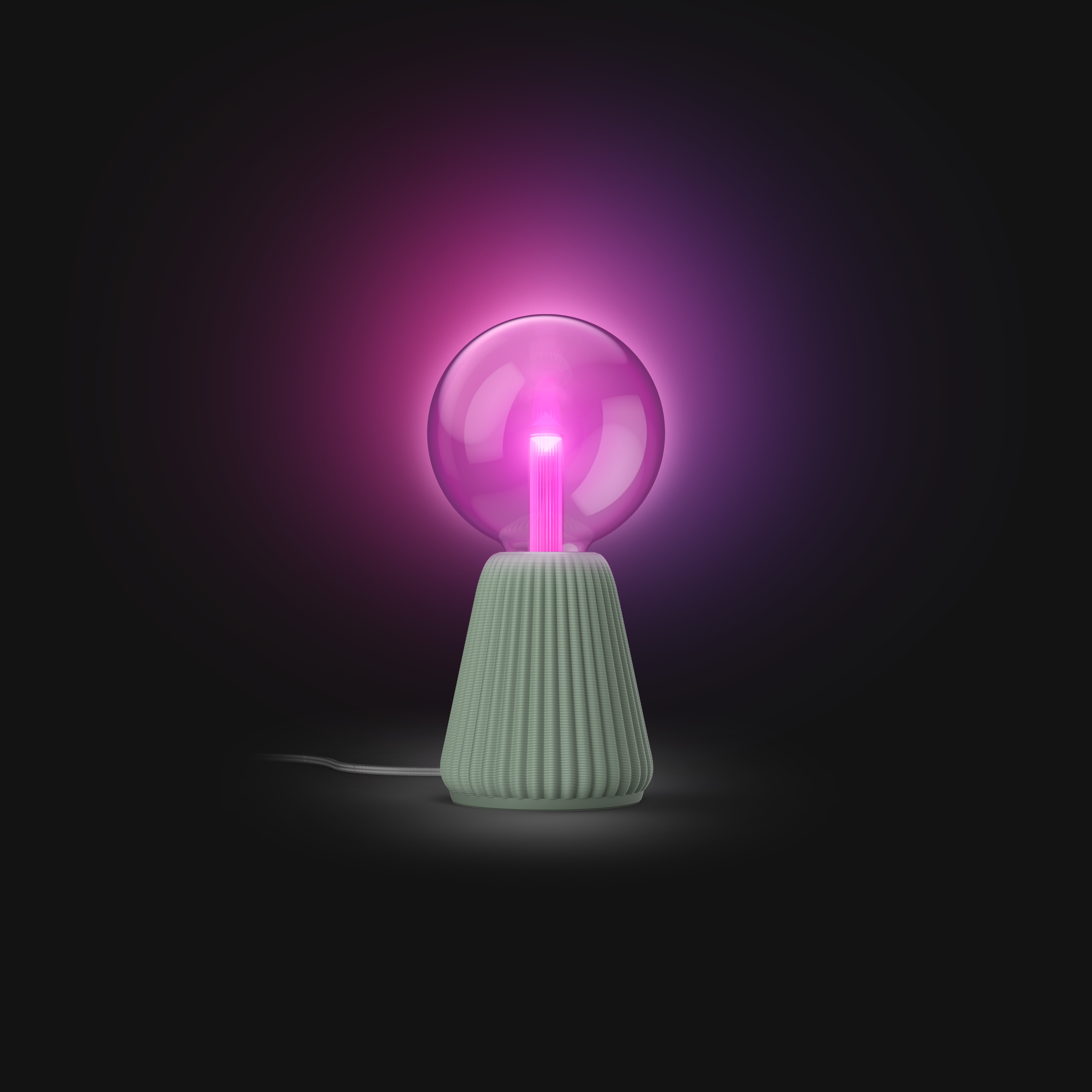 Una piccola lampada con base verde scanalata e lampadina rotonda rosa luminoso, su sfondo scuro.