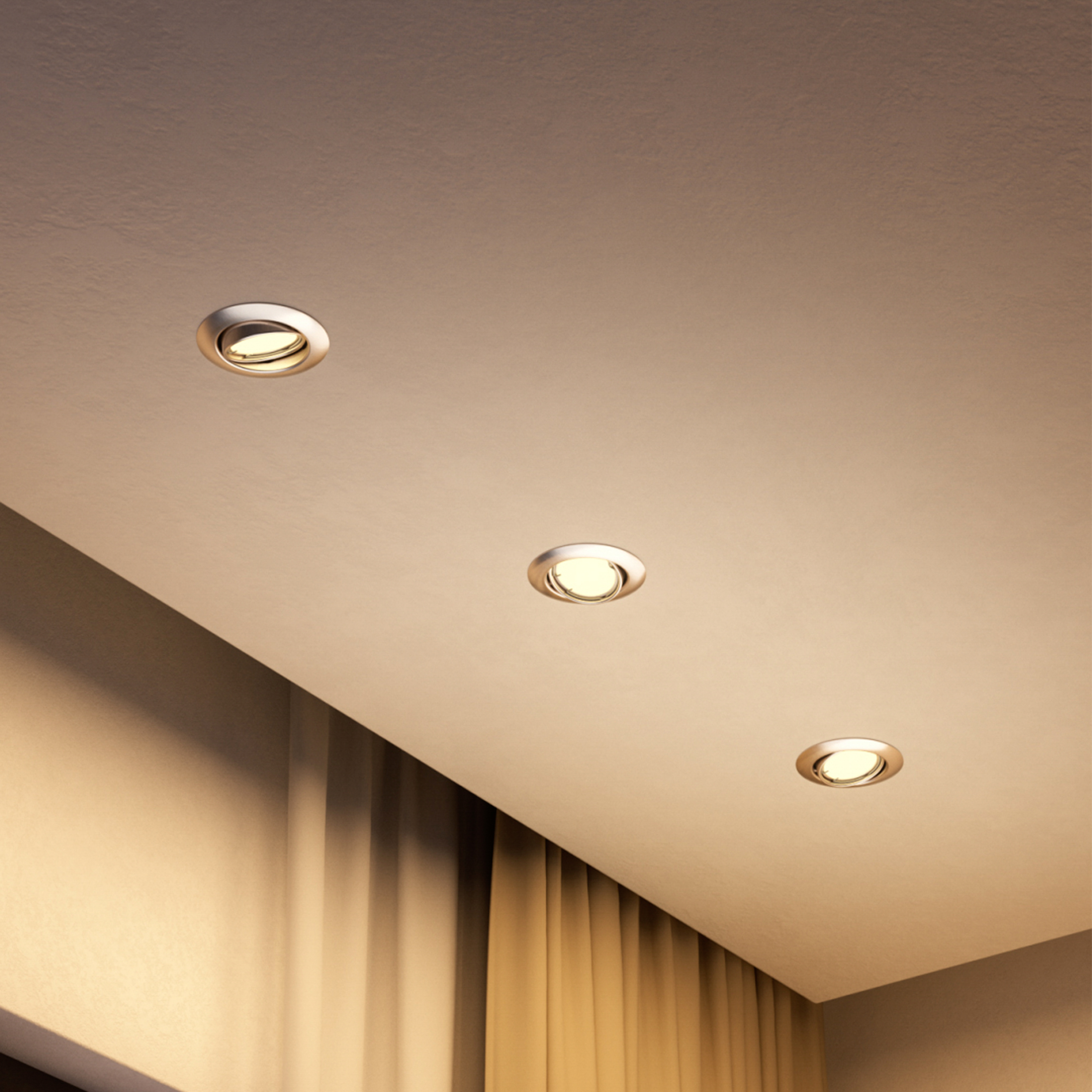 Tre faretti da incasso rotondi a luce calda in un soffitto chiaro, con tende dorate che incorniciano il fondo.