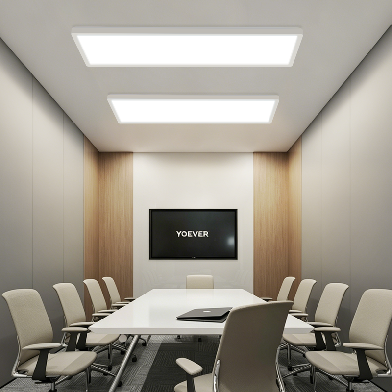 Moderner Konferenzraum mit langem weißen Tisch, beige Stühlen, Bildschirm und heller Deckenbeleuchtung.