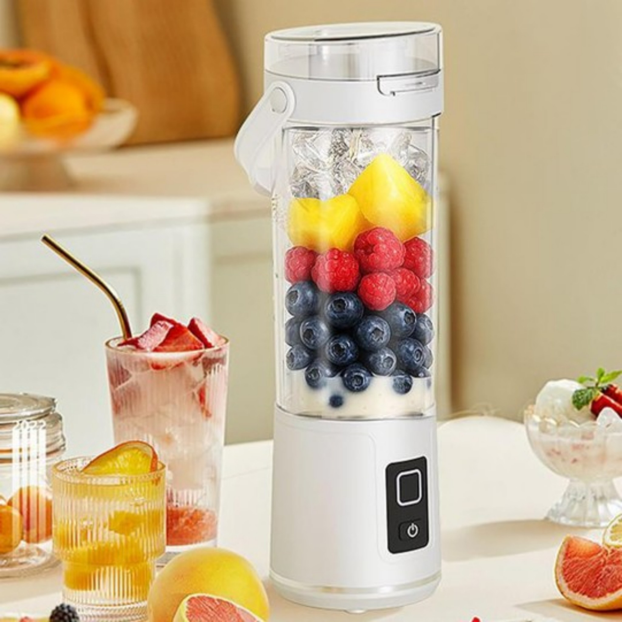 Ein weißer tragbarer Mixer gefüllt mit Eis, gelben Mangostücken, Himbeeren und Blaubeeren auf einem Tisch.
