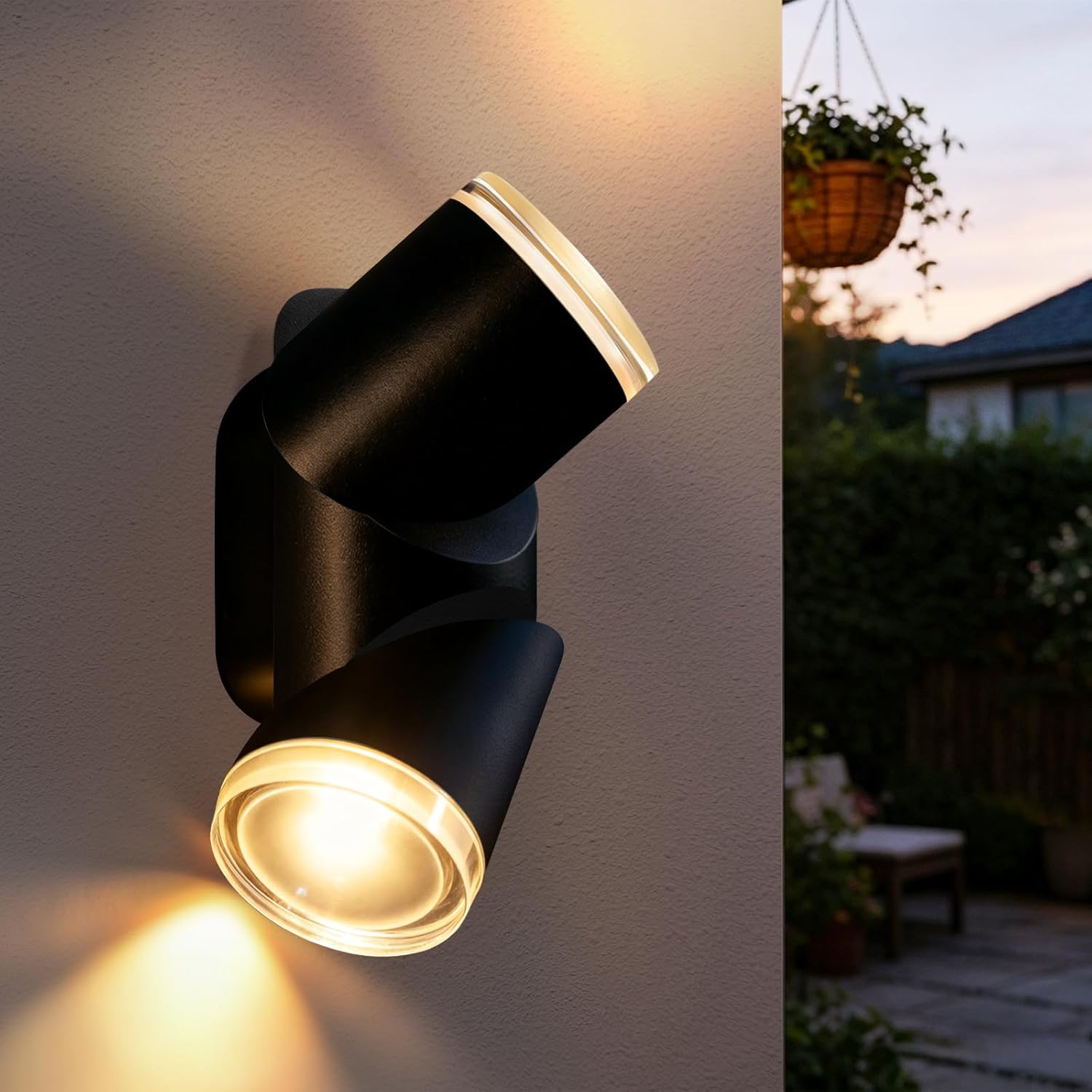 Eine schwarze Doppelwandleuchte mit warmem Licht an einer hellen Hauswand, im Hintergrund eine Terrasse.