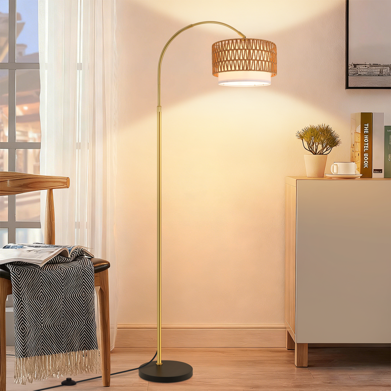 Goldene Bogenlampe mit Rattanschirm im hellen Wohnzimmer neben Stuhl und Schrank.