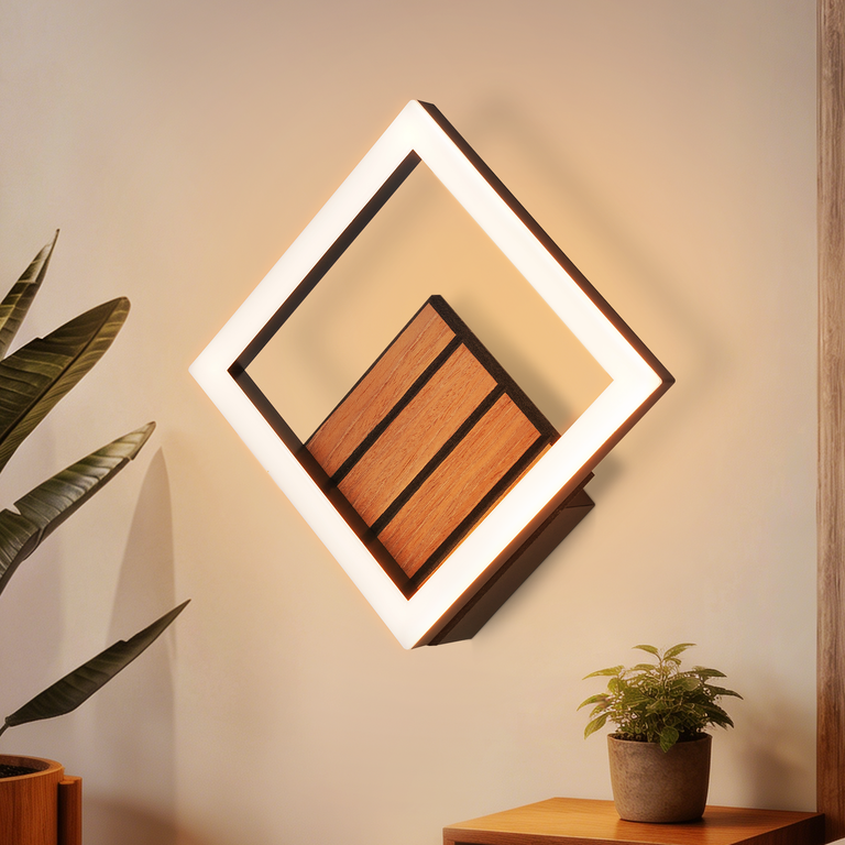 Eine quadratische LED-Wandleuchte mit Holzakzenten hängt an einer hellen Wand, flankiert von Zimmerpflanzen.