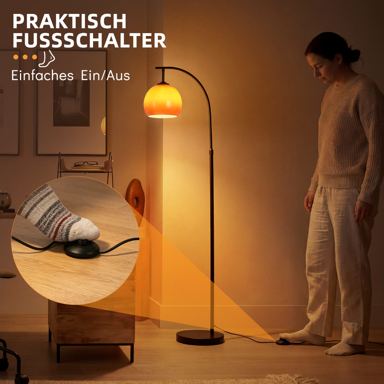 Eine Frau schaltet eine Bogenlampe mit orangefarbenem Schirm per Fußschalter an.