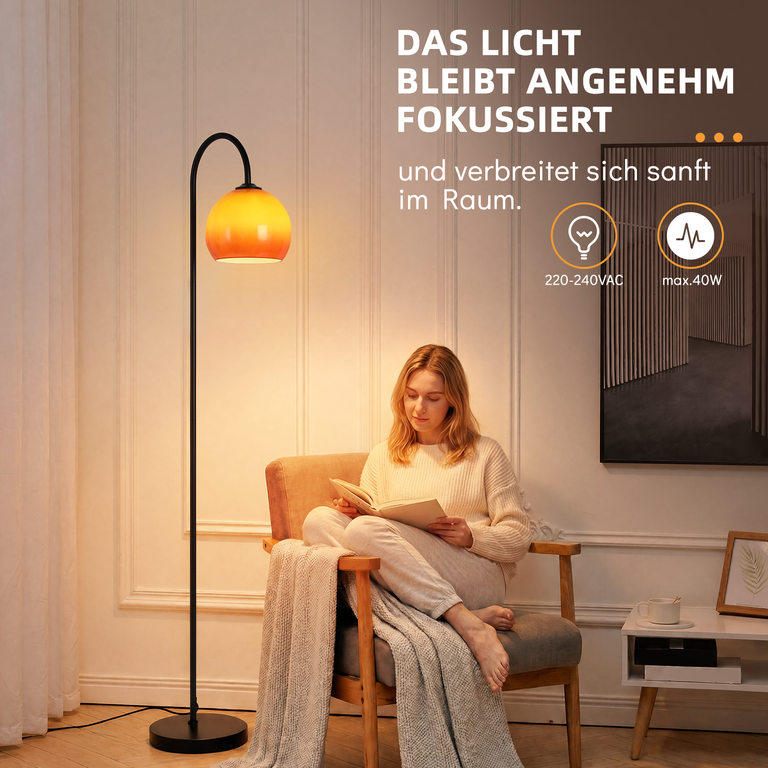 Eine Frau sitzt im Sessel und liest, beleuchtet von einer schwarzen Stehlampe mit orangefarbenem Schirm.