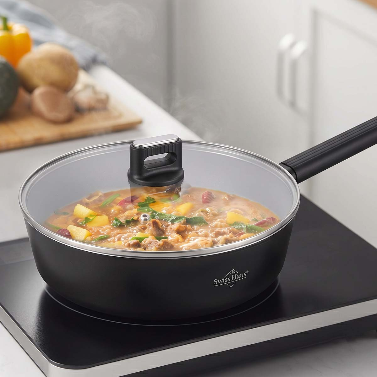 Una sartén Swiss Haus tapada con guiso hierve a fuego lento en una placa de inducción, con verduras en una tabla de cortar al fondo.