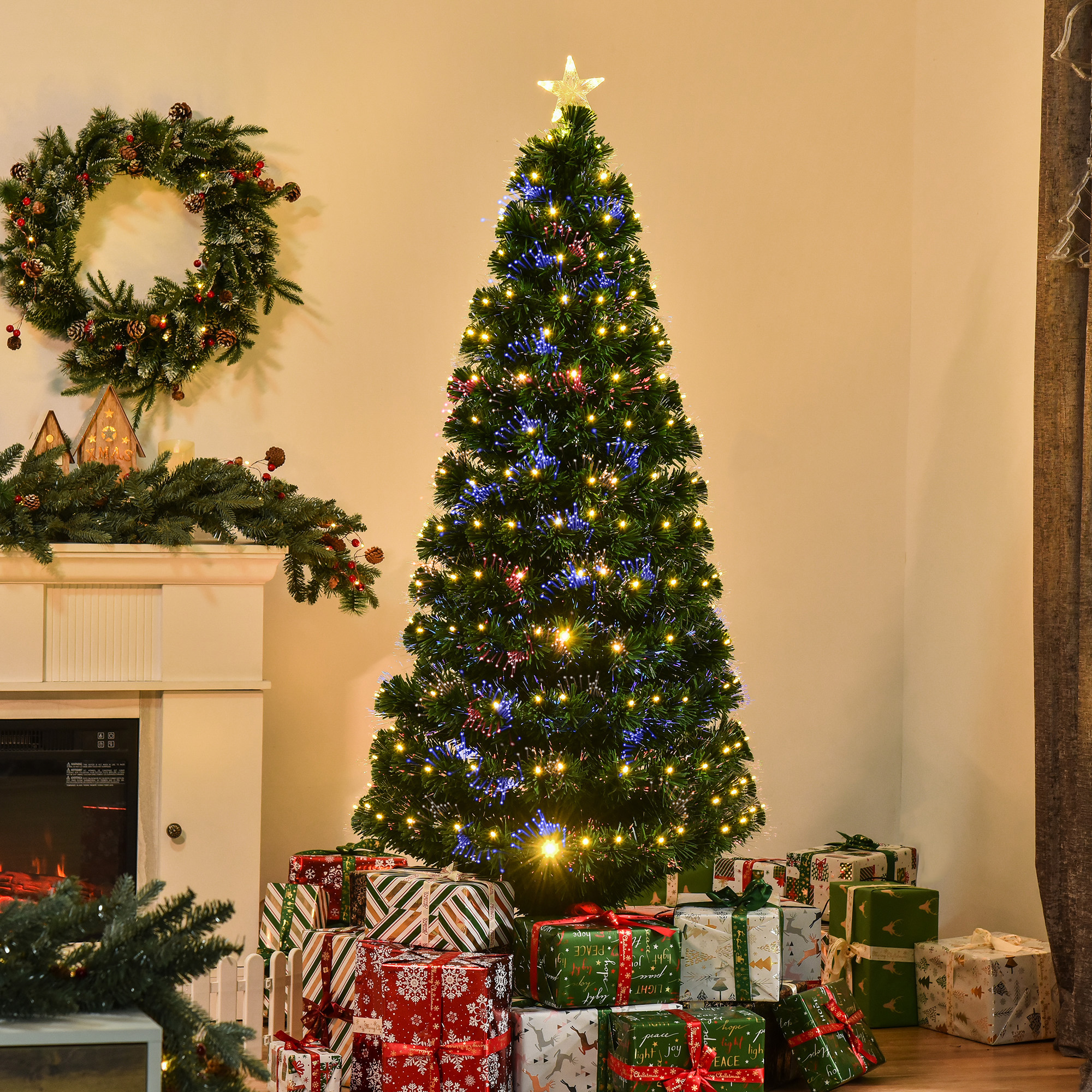Árbol de Navidad iluminado con estrella, regalos, chimenea y corona de pared.