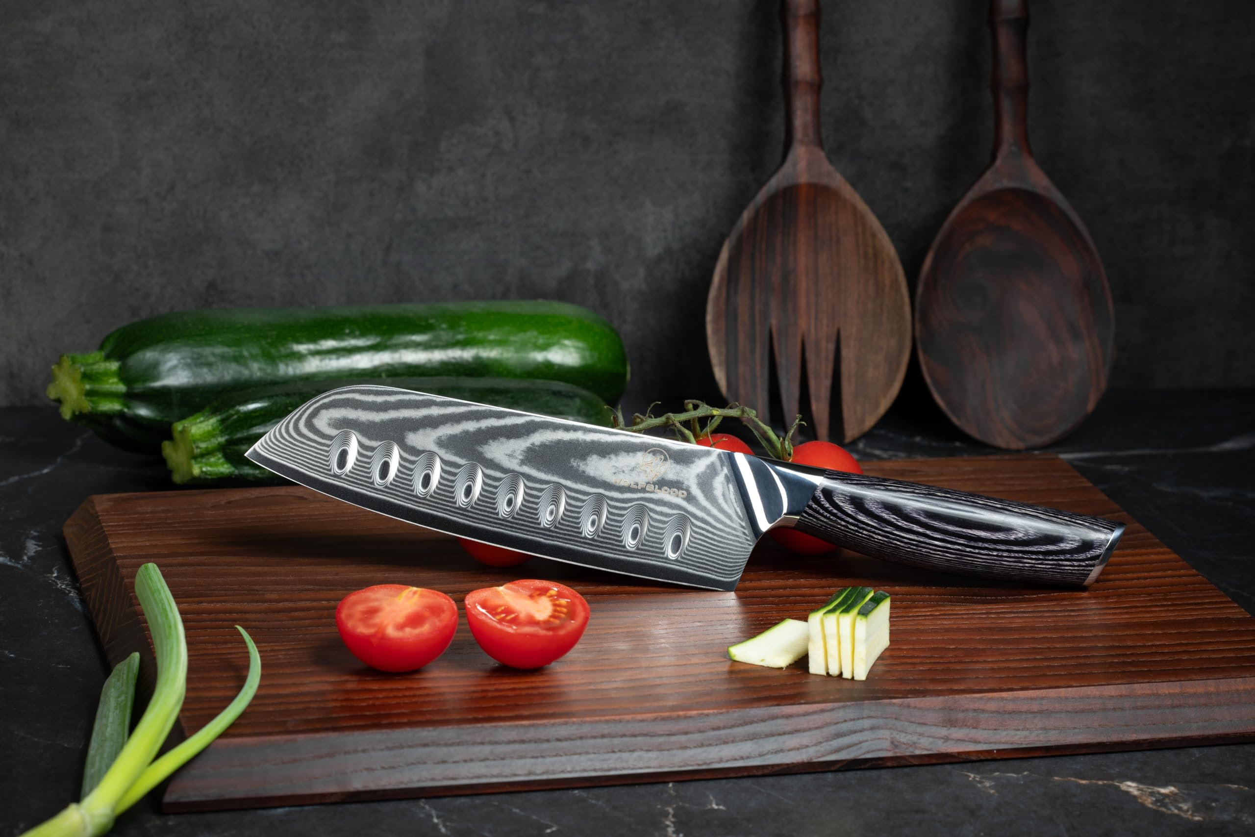 Un couteau damasquiné repose sur une planche en bois avec des tomates, des courgettes et des oignons.
