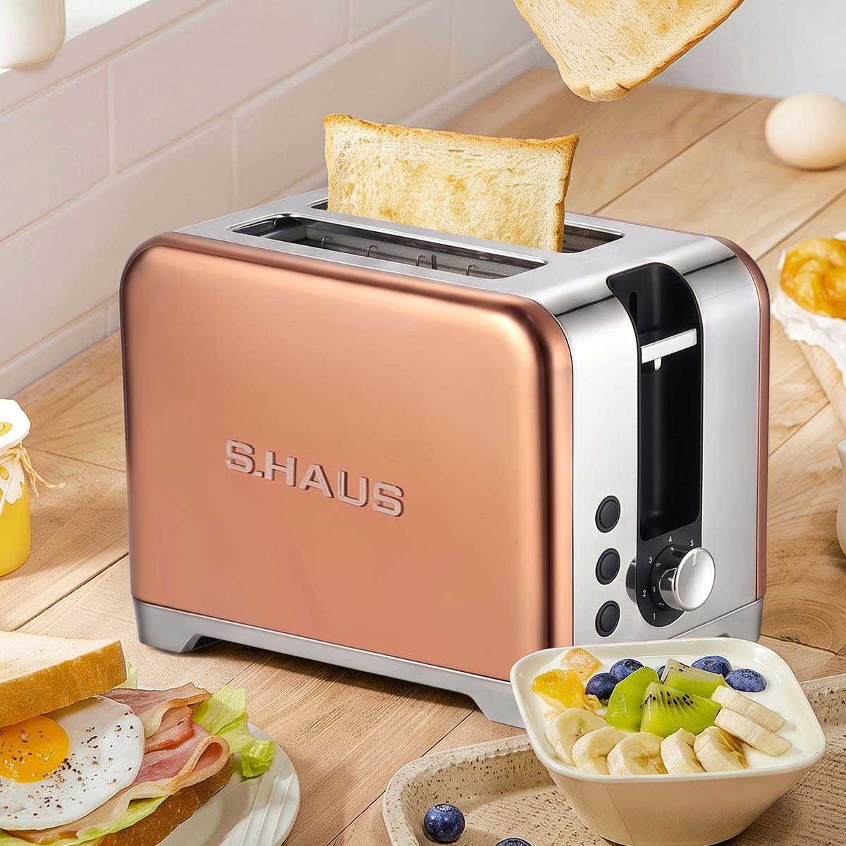 Ein roségoldener Toaster auf einer Holzplatte mit Brot, Ei und Joghurt.