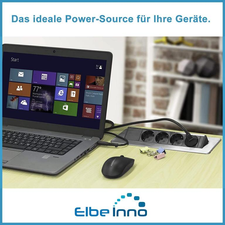 Ein Laptop steht auf einem Schreibtisch neben einer integrierten Mehrfachsteckdose und einer schwarzen Maus.