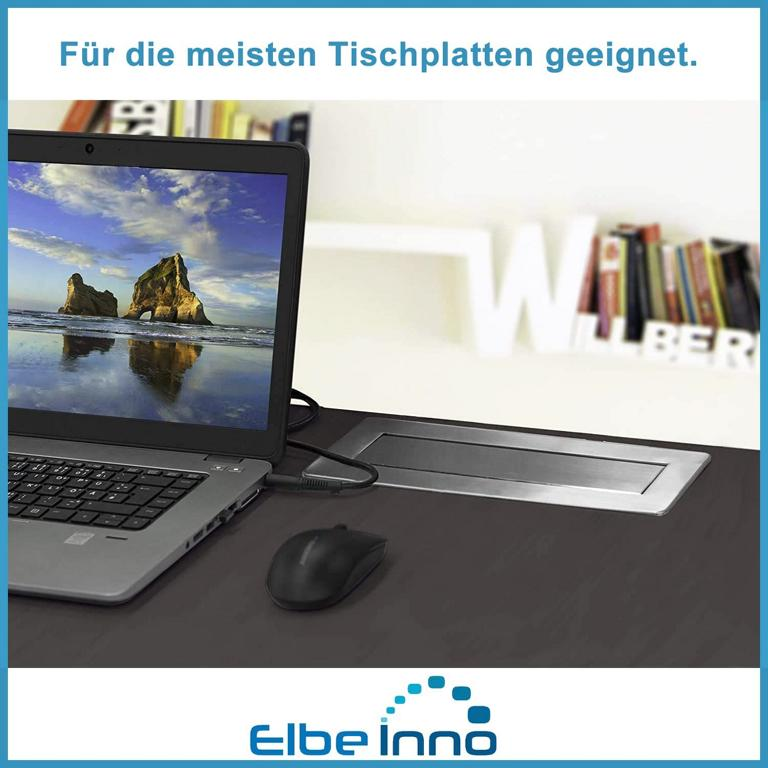Ein Laptop, eine Maus und eine integrierte Steckdose auf einem dunklen Schreibtisch.