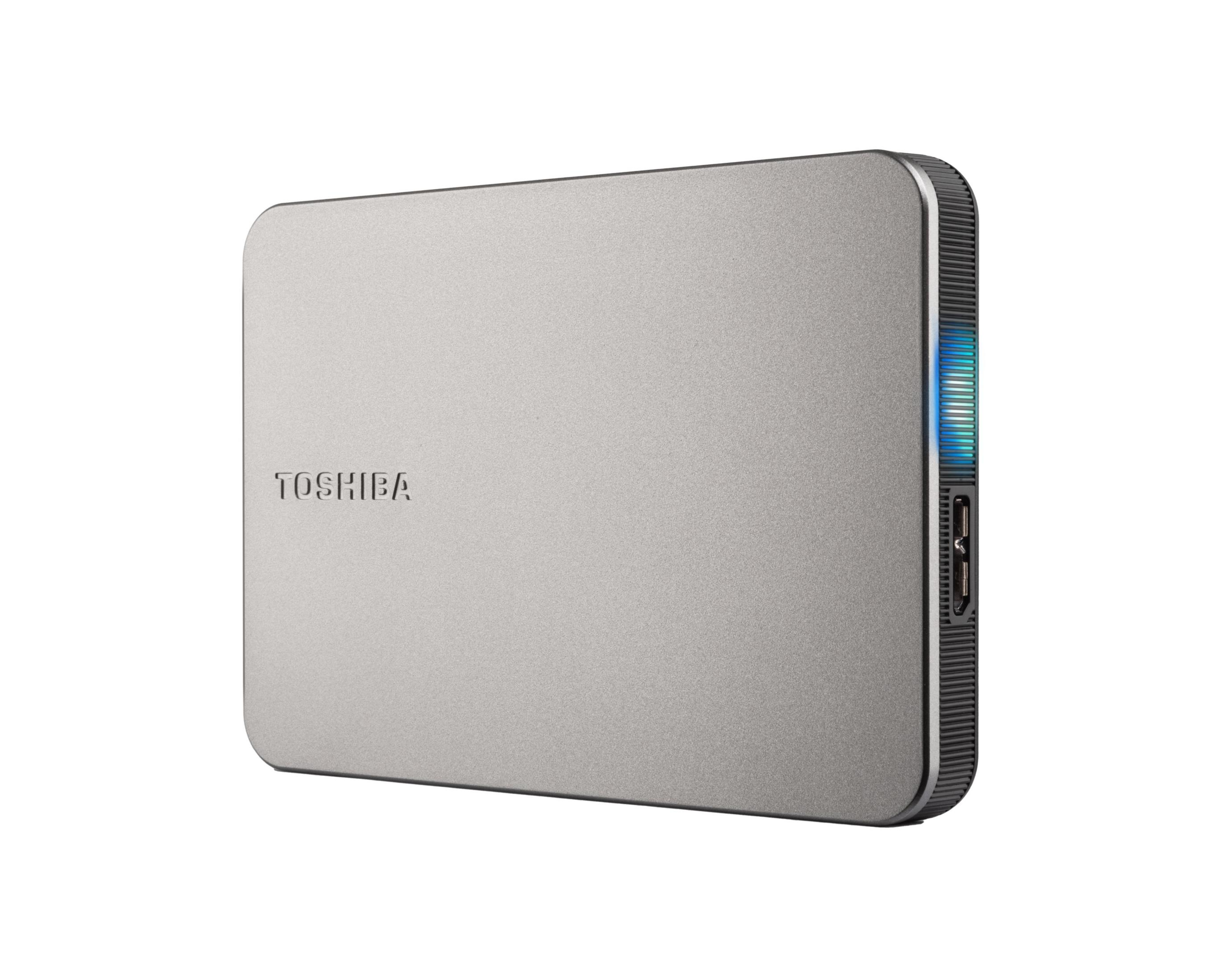 Un disco rigido esterno Toshiba argentato con una luce di stato blu brillante e una porta sul lato.