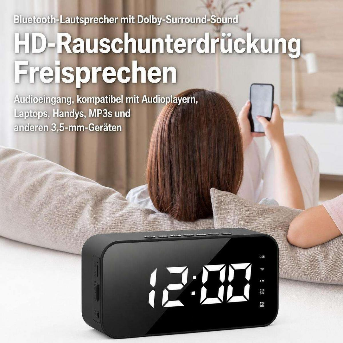 Ein schwarzer Digitaler Wecker auf einem Tisch, im Hintergrund sitzt eine Person mit einem Smartphone auf der Couch.