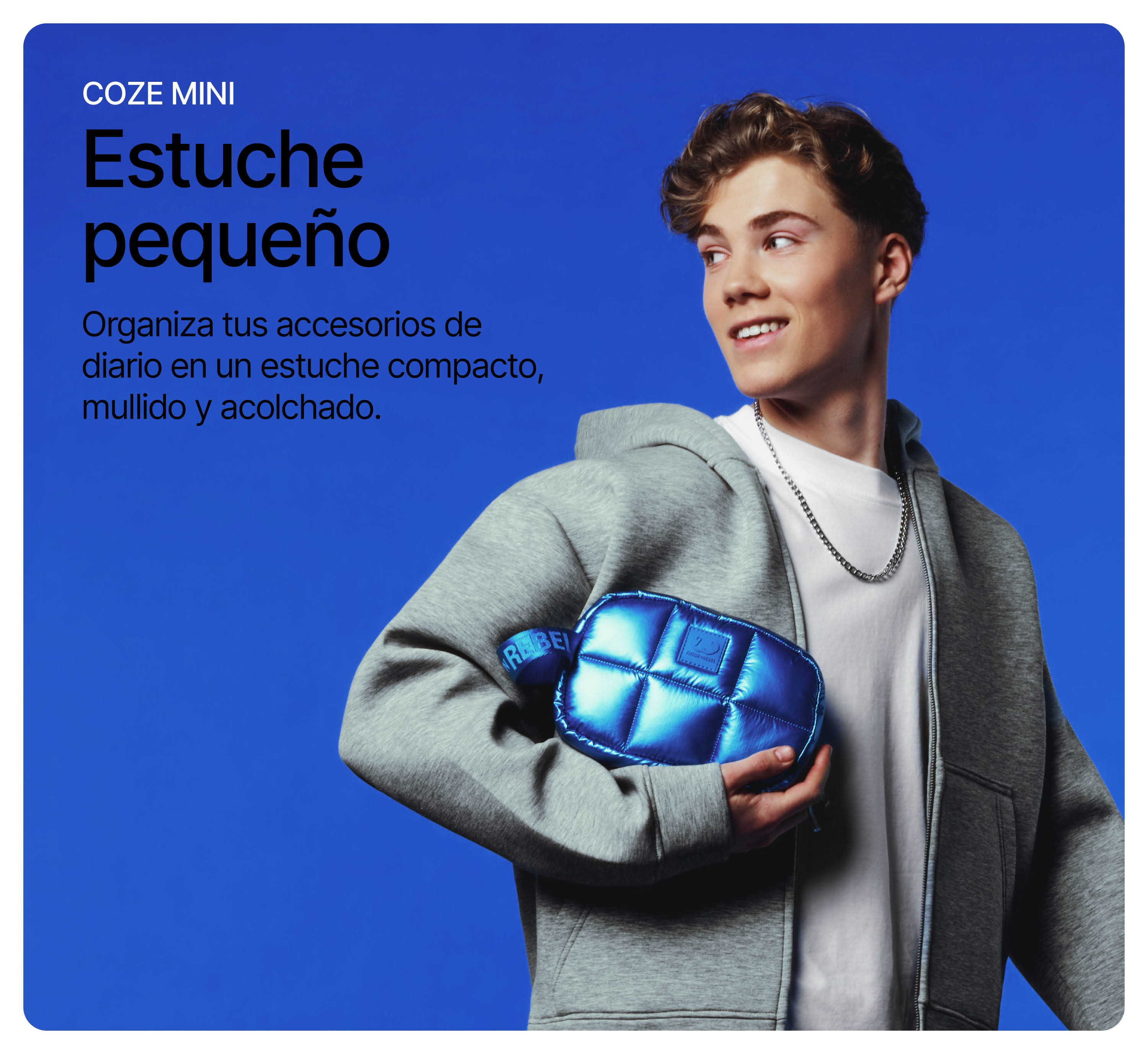 Ein junger Mann im grauen Hoodie hält eine glänzende blaue Tasche vor blauem Hintergrund.