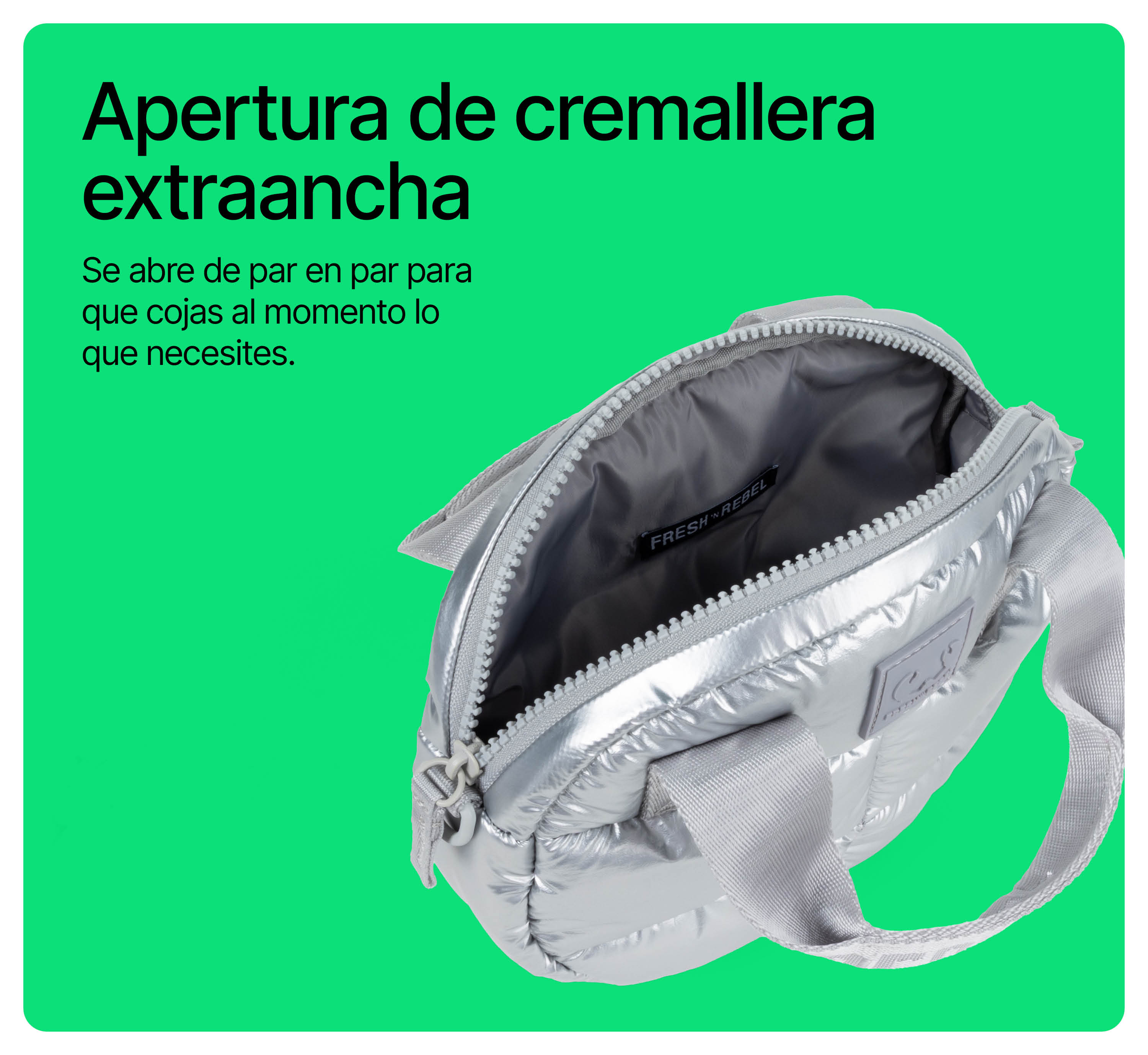 Bolso plateado acolchado abierto con cremallera ancha y asas grises sobre fondo verde.