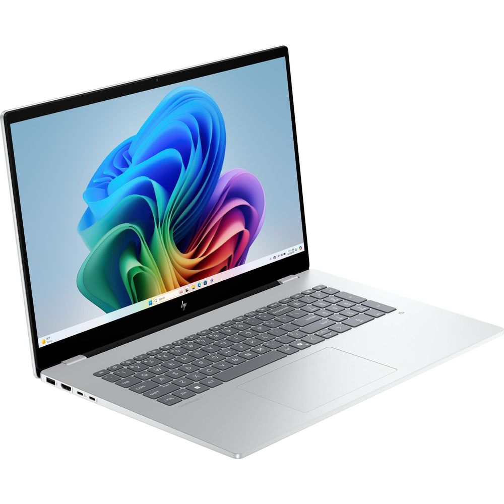 Un computer portatile argentato con uno sfondo astratto e colorato e tastiera grigia, visto di lato.