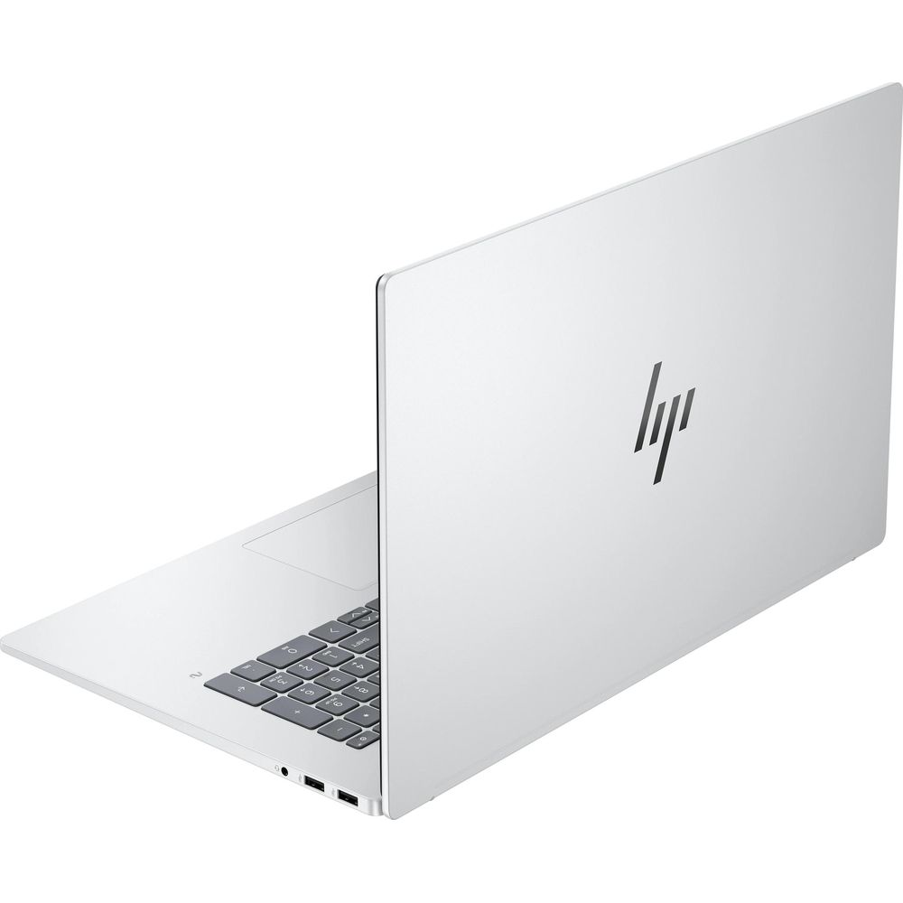 Un laptop HP argentato è leggermente aperto su una superficie bianca, mostrando la tastiera e il logo.