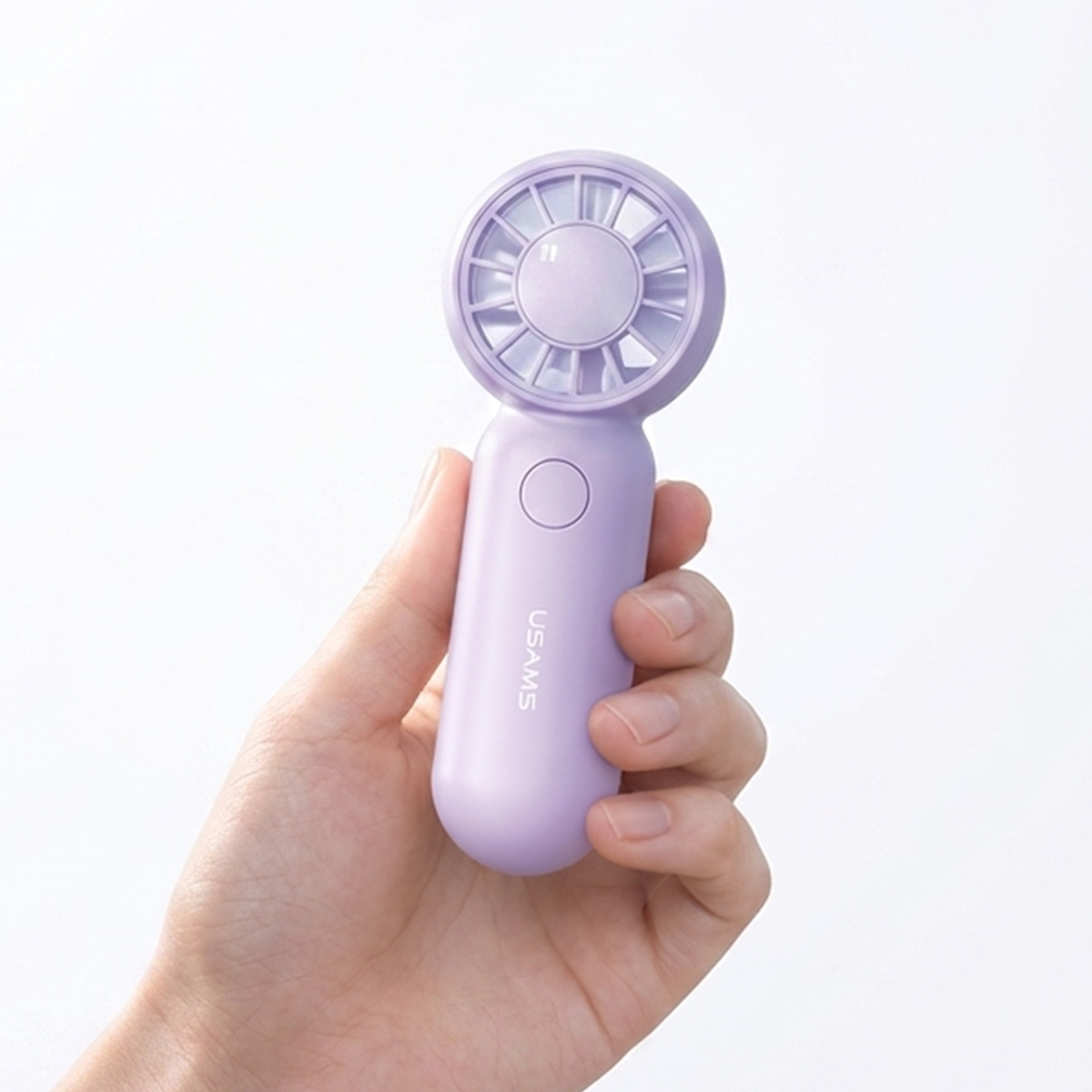 Eine Hand hält einen kleinen, hellvioletten tragbaren Handventilator vor einem weißen Hintergrund.