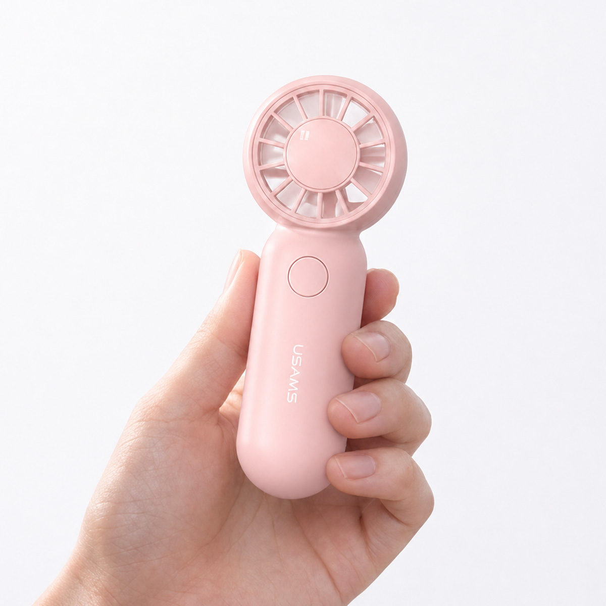 Eine Hand hält einen kleinen, rosa Handventilator vor einem weißen Hintergrund.