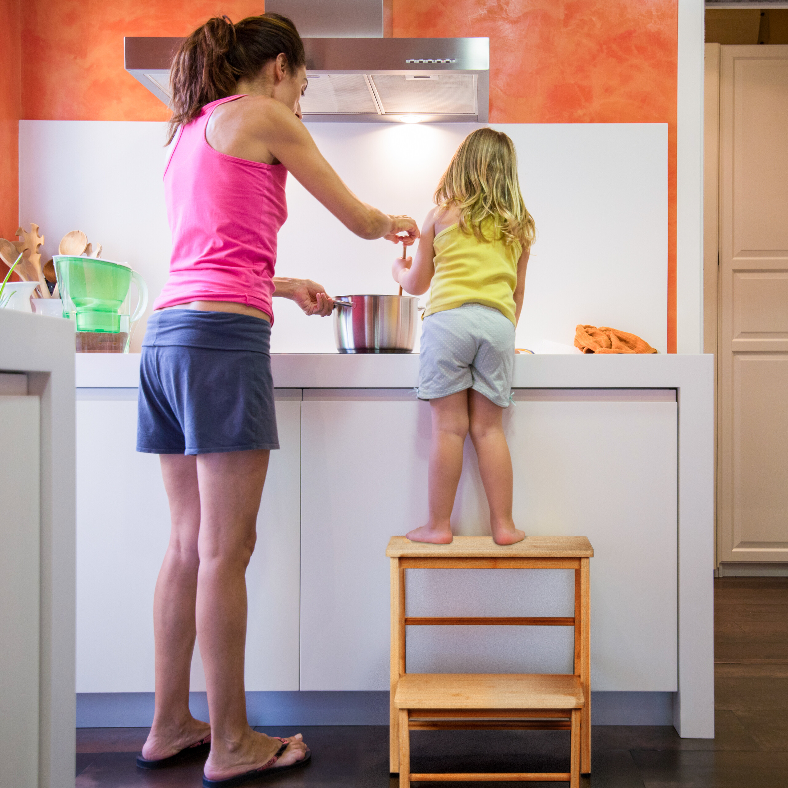 Eine Frau und ein Mädchen kochen zusammen an der Theke in einer modernen Küche.